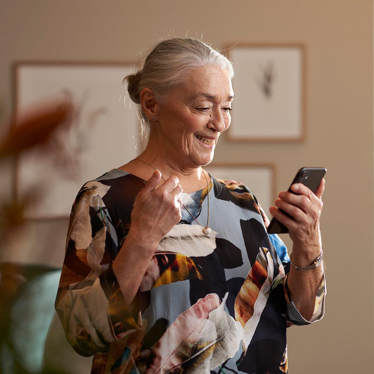 Mand, der bærer et par ReSound høreapparater og streamer lyd med sin iPhone.